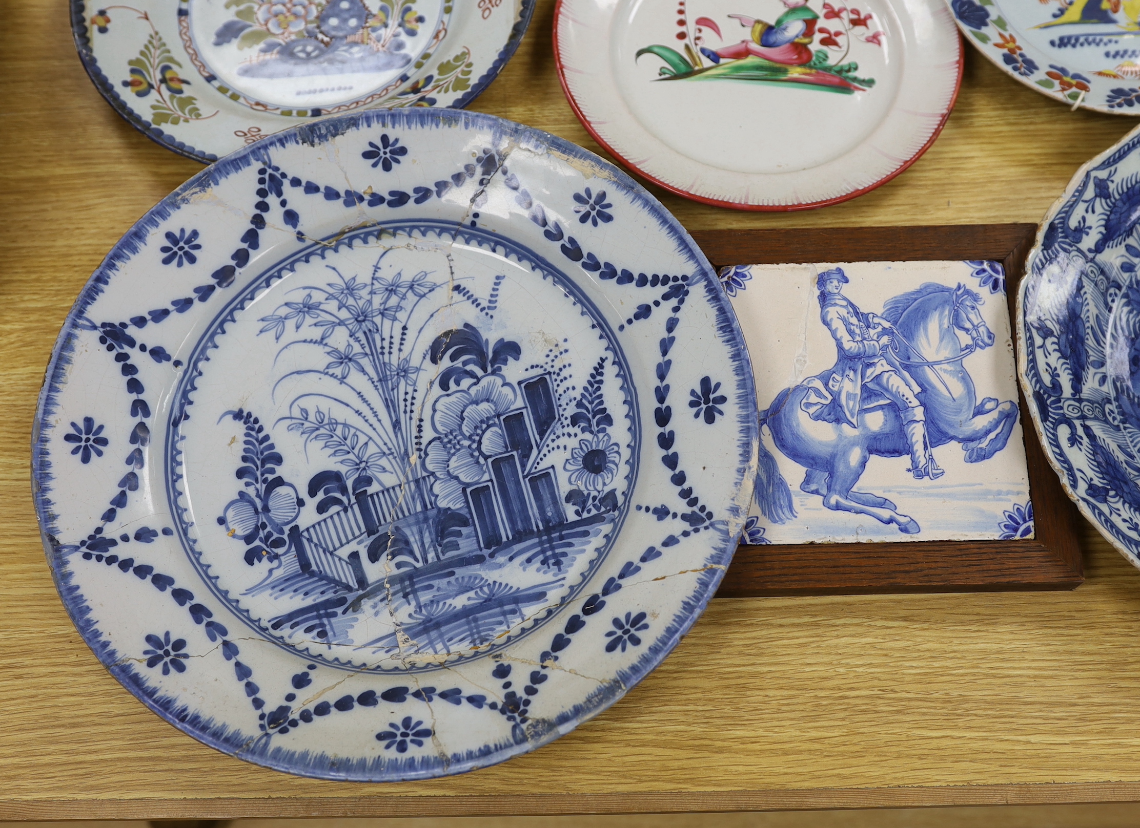 Two 18th century Delft blue and white dishes, a Delft polychrome dish, an English delftware plate, a Delft equestrian tile and a French faience plate, a.f., largest diameter 35cm